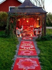 a super bold boho patio done in red and white, with white furniture and lots of red printed textiles