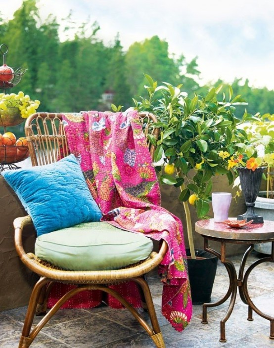 a colorful boho patio with rattan furniture, bright textiles, potted greenery and trees