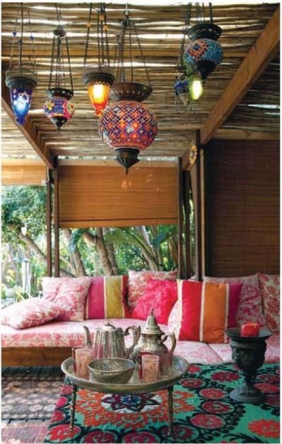 A bold Moroccan inspired patio with a colorful sofa and pillows, rugs and Moroccan style lanterns