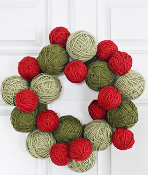 To make this door adornment, wrap Styrofoam balls and a Styrofoam wreath form with colored yarn. Glue everyting together with a hot glue gun. Don't forget to mix different shades of green and red yarn to make the wreath looks special.