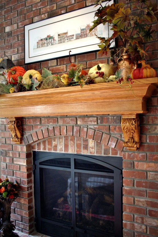 a lush fall mantel decorated with faux leaves, pumpkins, gourds, berries and other fall-related stuff