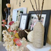 faux pumpkins, faux leaves, vases wrapped with yarn, branches, candles and vine pumpkins
