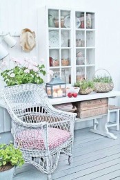 a delicate neutral decor with a console table with blooms, a wicker chair with a pink cushion and some baskets with greenery