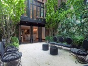 a contemporary townhouse terrace with a stone floor, a living wall and trees plsu catchy black furniture