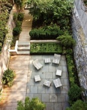 a contemporary townhouse garden with a wooden deck and concrete tiles, contemporary furniture and planted greenery