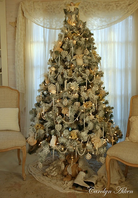 a beautiful white Christmas tree with lights, beads and ornaments in white and silver and some vintage toys under the tree