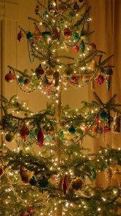 a Christmas tree with lights, bead garlands and colorful Christmas ornaments in red, green and pink
