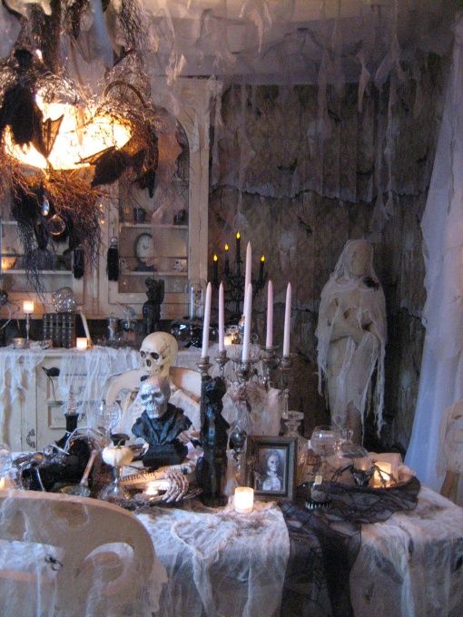 a stunning vintage Halloween haunted space with net as spider webs, tall candles, skulls and skeletons, blackbirds and bats is a cool idea for a party