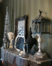 a vintage Halloween mantel with spider webs, skulls, pumpkins, statuettes, a black cage and white pumpkins is a chic and cool idea