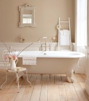a very relaxing and peaceful taupe and beige bathroom with vintage furniture and a clawfoot bathtub