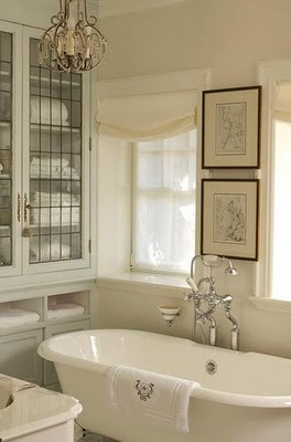 A creamy and off white bathroom with artworks in dark frames for a chic space