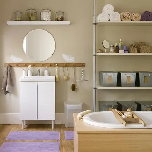 A taupe and light colored wood bathroom with some white furniture and stainless steel