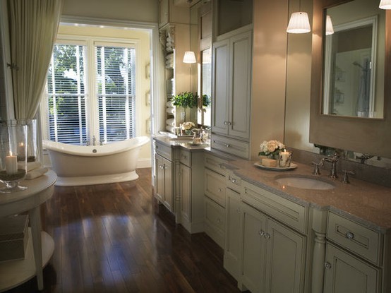 a beige, creamy and brown bathroom with curtains, a dark wooden floor and a large window