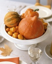 a bowl with gourds and pumpkins and some fruit is a lovely and very easy Thanksgiving centerpiece to make it last minute