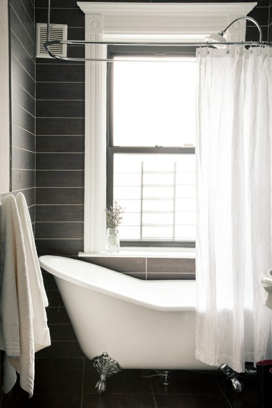 Black tiles and a clawfoot bathtub behind a white curtain is one of those combos that can't go wrong.