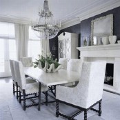 a vintage black and white dining space with a fireplace, a dining table and neutral chairs, a crystal chandelier and creamy curtains