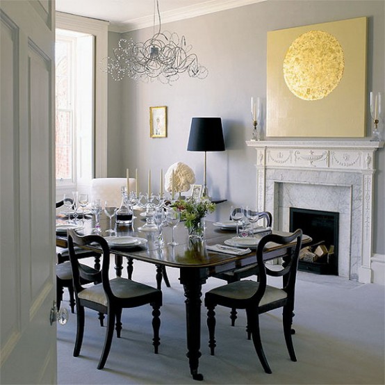 a neutral dining room with a non-working fireplace, an elegant black dining set and a crystal chandelier