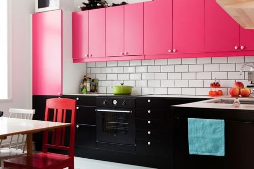 a bold kitchen with lower black cabinets, hot pink upper cabinets, red chairs and a white subway backsplash is cheerful and chic
