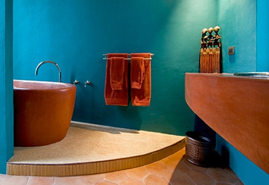 a bright blue bathroom with rust-colored touches and furniture for a bold modern space