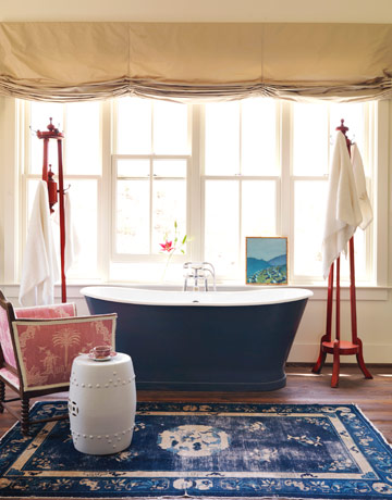 a vintage navy and blue rug plus a navy bathtub to add color and interest to the space