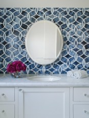 navy mosaic tiles, a white vanity and a round mirror for a stylish bathroom sink space