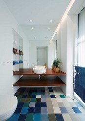 a bright color block tile floor including blues and a matching bold blue towel for a contemporary bathroom