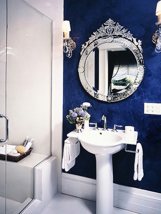 a navy textural wall and a mirror in a refined and chic frame adds a luxurious touch to the space