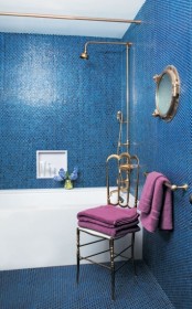 bright blue penny tiles paired with brass fixtures and a porthole create a cool bold look with a nautical feel