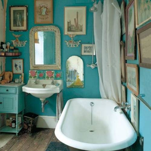 bright turquoise walls with lots of artworks for a vintage and eclectic bathing space
