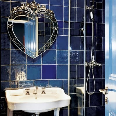 Mismatching blue and navy tiles on the wall and a refined heart shaped mirror for a luxurious space