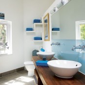 a sleek light blue half wall and bright blue towels for a contemporary bathroom