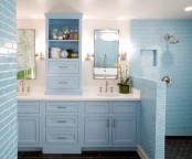 a serenity blue bathroom done with tiles with white grout and a vintage storage unit and vanity