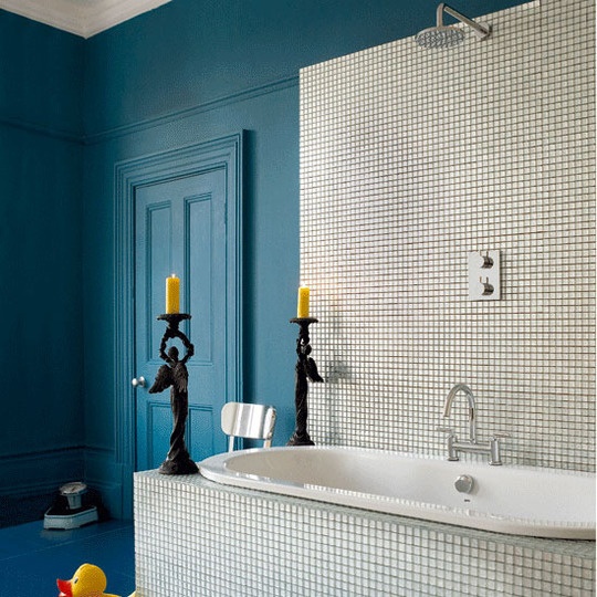 a bright blue bathroom with a bathtub accented with neutral tiles and a backsplash of them