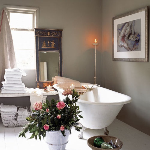 a clean bathroom with grey walls, a chic clawfoot tub, white towels and a gorgeous mirror in a unique frame