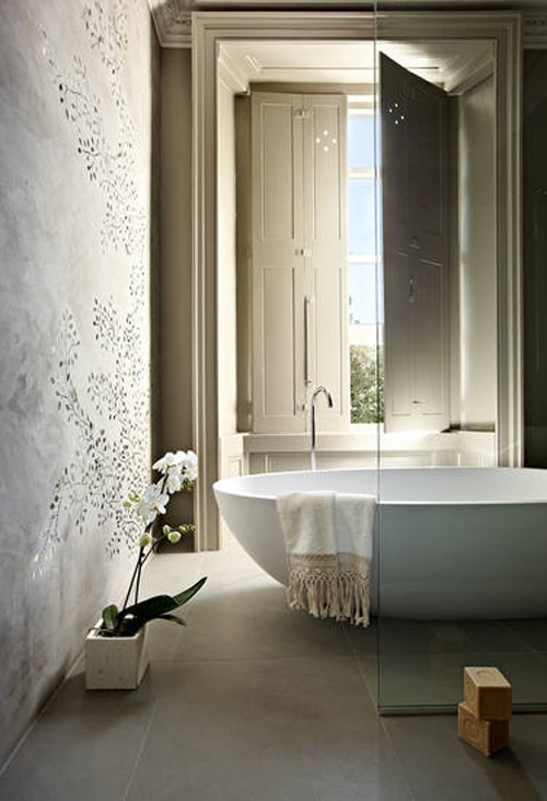 a neutral bathroom with plaster walls, a large tub and handmade soaps right on the floor