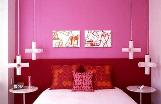 a bold pink bedroom with a burgundy bed and red pillows, catchy pendant lamps and artworks is a statement space that catches an eye