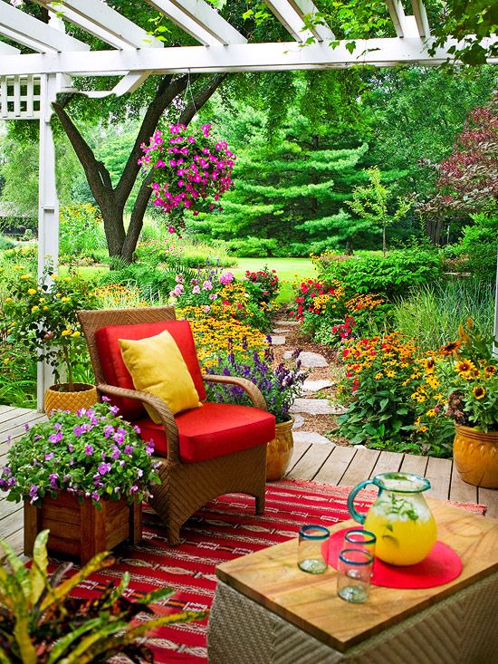 a colorful spring terrace with a boho feel, with wicker furniture, bright blooms and greenery and bold pillows and upholstery