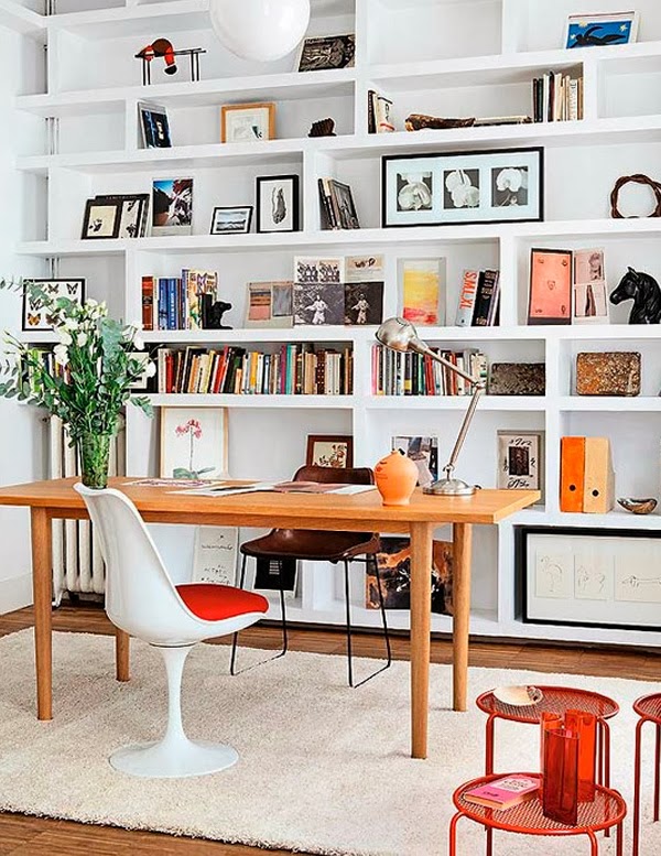 A welcoming and light filled home office with a whole wall of built in shelves and some furniture is a cool space to work