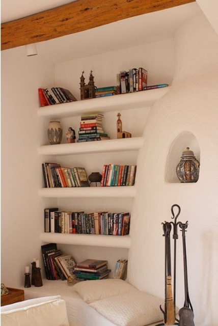 A concrete white wall with built in shelves where you can place books and other stuff you want