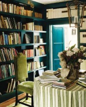 a refined home library with blue built-in bookshelves taking all the walls is a very stylish and cool idea