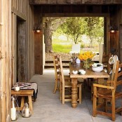 an outdoor rustic dining room with a vintage wooden dining set, candle lanterns and yellow blooms on the table is a great and welcoming space