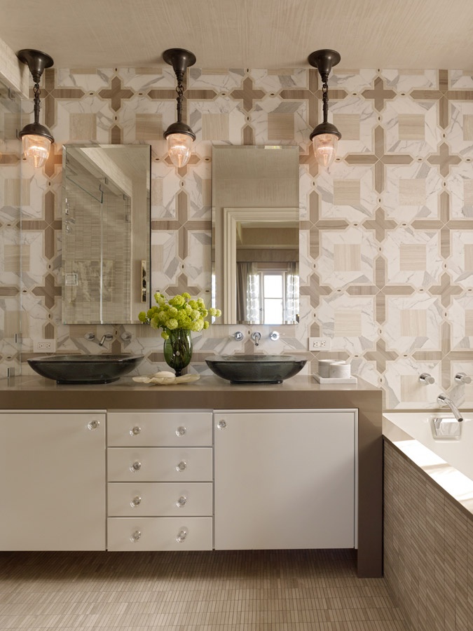 A neutral modern bathroom with a built in vanity, mismatching tiles, two tinks and mirrors and vintage pendant lamps