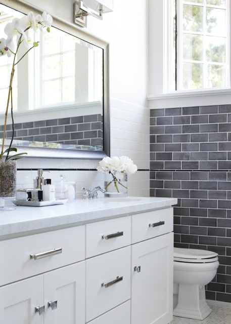 a serene neutral bathroom with grey and white tiles, a white vanity, a large mirror and white blooms for a refined touch