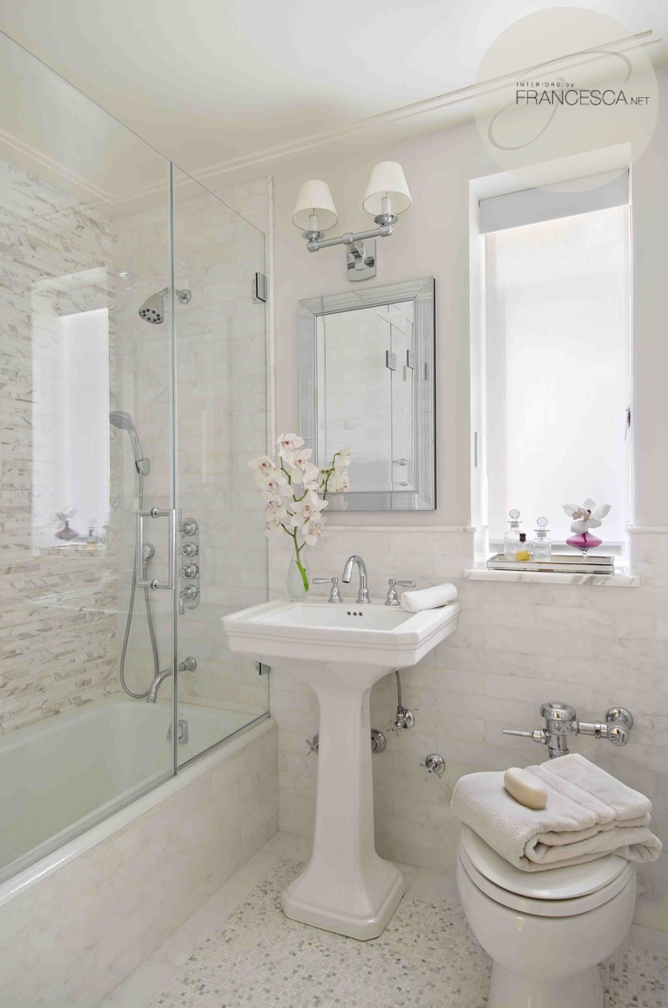 A refined neutral modern bathroom clad with various types of tiles, a free standing sink and white appliances plus a mirror and a sconce over the mirror