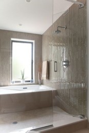 a tan bathroom clad with skinny tiles, a bathtub clad with tiles, too, and a window with frosted glass is amazing