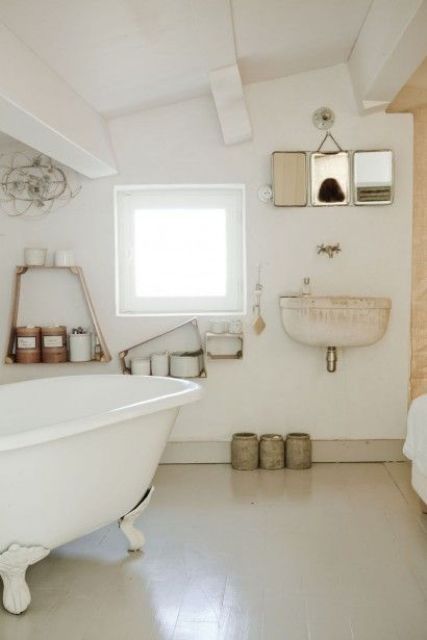 A neutral and industrial vintage bathroom with a clawfoot tub, open shelves, mirrors and a wall mounted sink