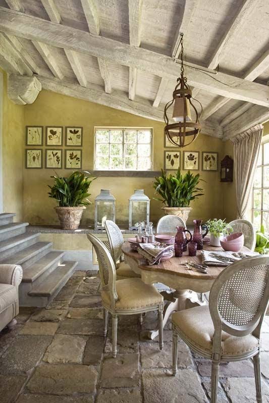 a Provence dining room with buttermilk walls, a vintage dining table and neutral refined chairs, with a stone floor and a whitewashed attic ceiling