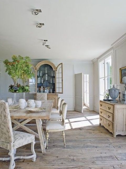 a vintage Provence dining space with whiewashed vintage furniture, a large stained vintage buffet, greenery and artwork
