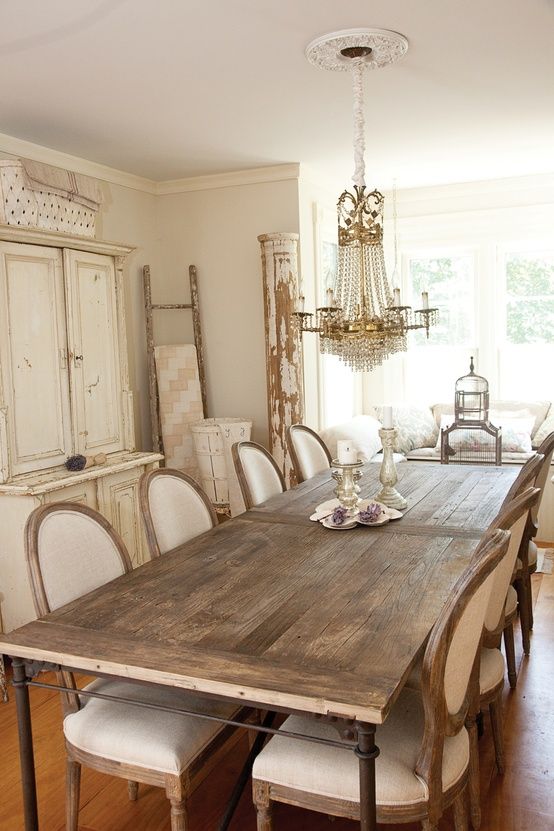 a shabby chic Provence dining room with a vintage storage unit, a stained table, vintage chairs, a crystal chandelier and some refined decor