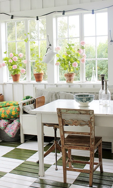 an eclectic vintage sunroom with shabby chic and vintage furniture, white and stained, colorful textiles and potted blooms